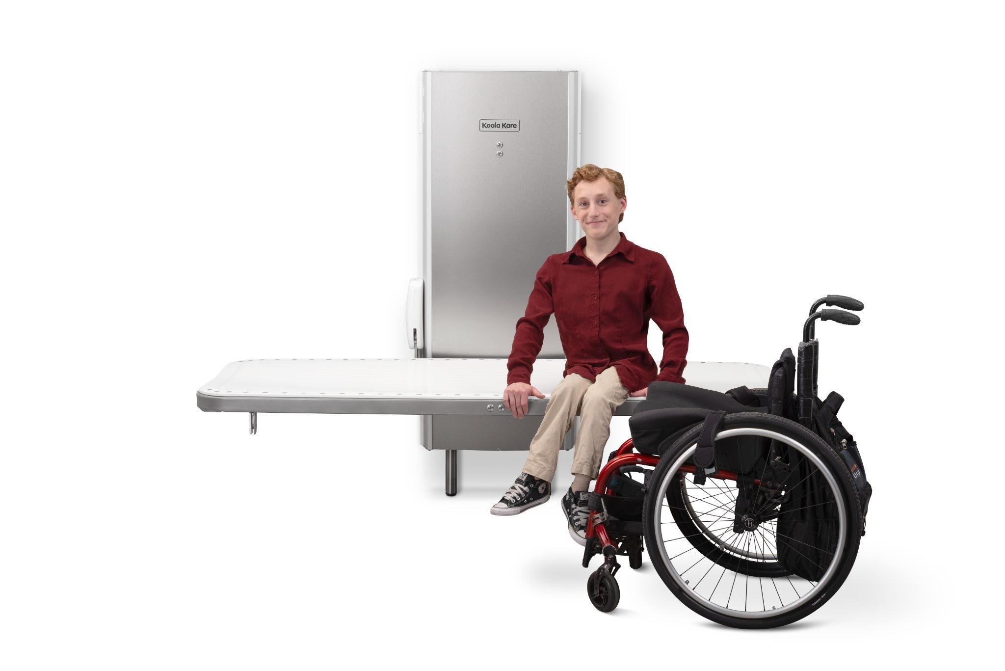 A man sits on the lowered table of Koala Kare Products’ KB3000 Adult Changing Station. 